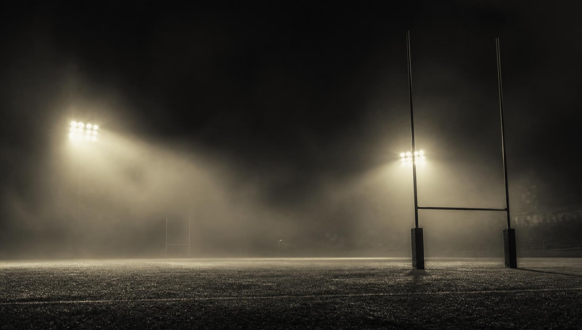 An empty rugby pitch at night under stadium floodlights